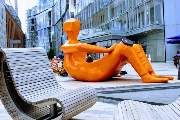 'Tea Break' - An orange figure reclining with a cup of tea outside Battersea Power Station