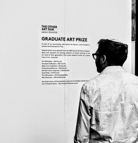 'Looking On' - A visitor to The Other Art Fair Looking on at the list of entries to the Graduate Art Prize