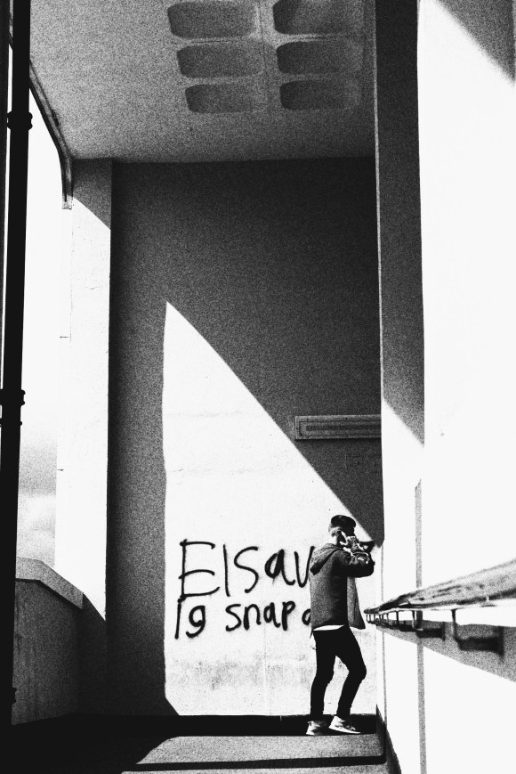 'Hello! Can you hear me?' - a grainy black and white picture of a young lad with his mobile to his ear as he walks up a covered footpath