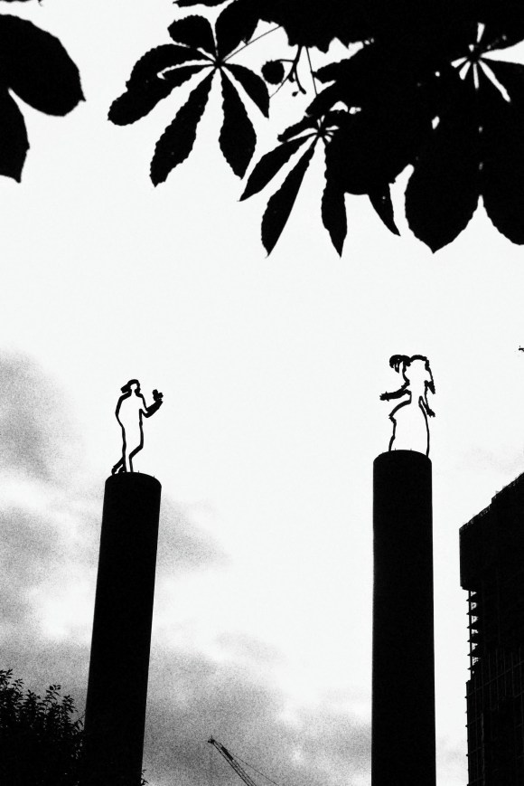 a black and white image showing the plinth mounted artwork of a lady in 18th century garb being offered a flower from a young man from the present day.