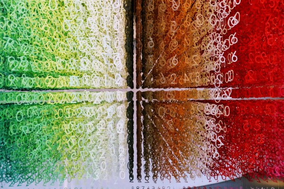 a view into a mass of numbers hanging from the ceiling. the numbers are delicately arranged so that they are allingned and coloured