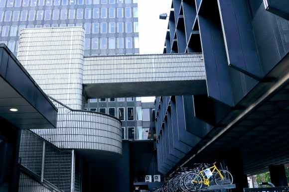a dull blue/grey view of a hidden part of Eustaon Plaza with a high rise view as the backdrop and the foregound focussing on a white tiles walkway and stairs