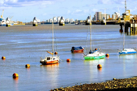 three yachts moored near the Thames south shore with the barrier in the near distance