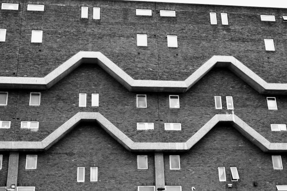 a black and white picture of the facade of Southwyck House in Brixton. Made up plain bricks, small windows and a zig-zag feature to brak up the plain view