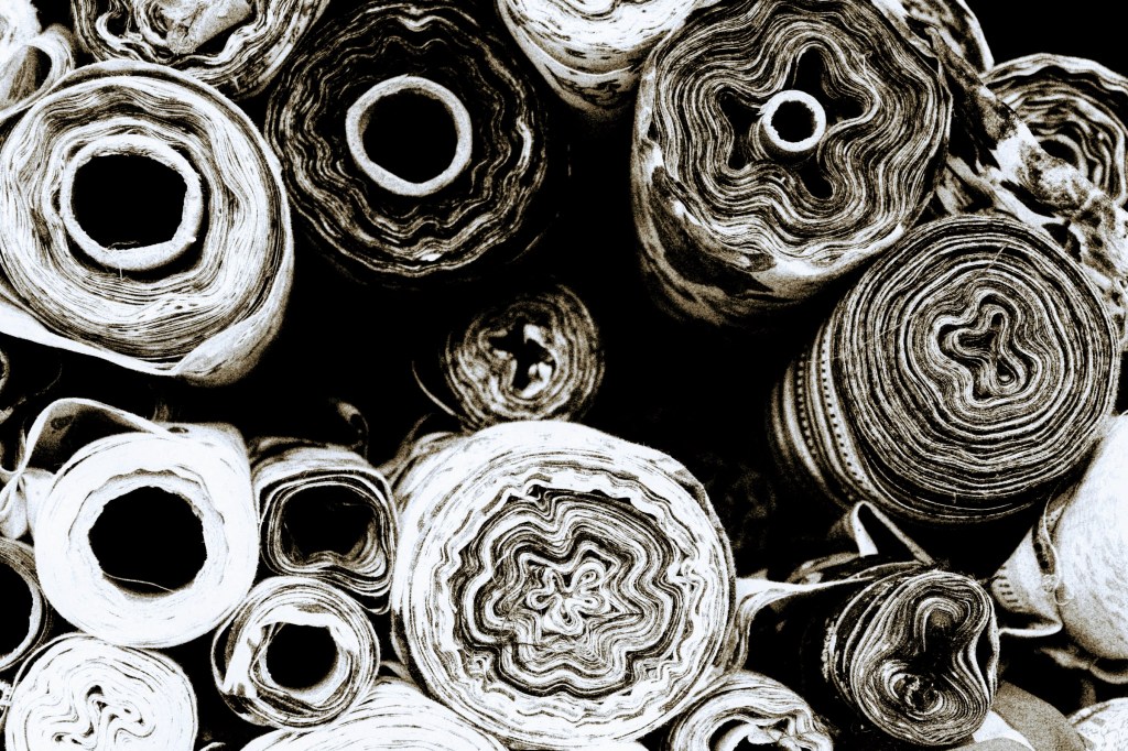 A saturated black and white photo of several ends of cloth rolls creating an array of circular patterns