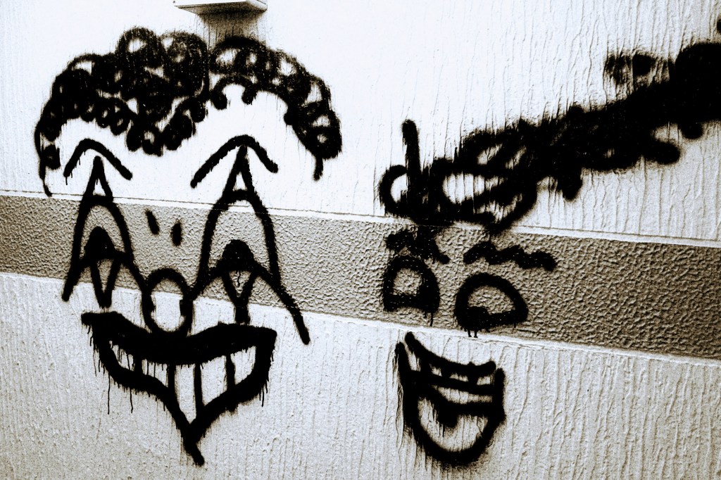 two clown'ish grafitti faces on a  car park wall in Romford