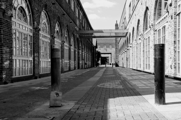 A view between two regenerated 'old railway works'. Taken in black and white with one side in the sun and the other in the shade