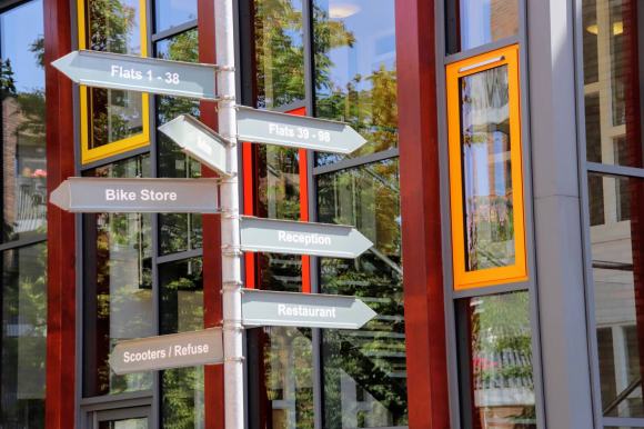 Outside the main reception building to Dreywood Court showing colourful windows and a sign post directing residents to different parts of the building