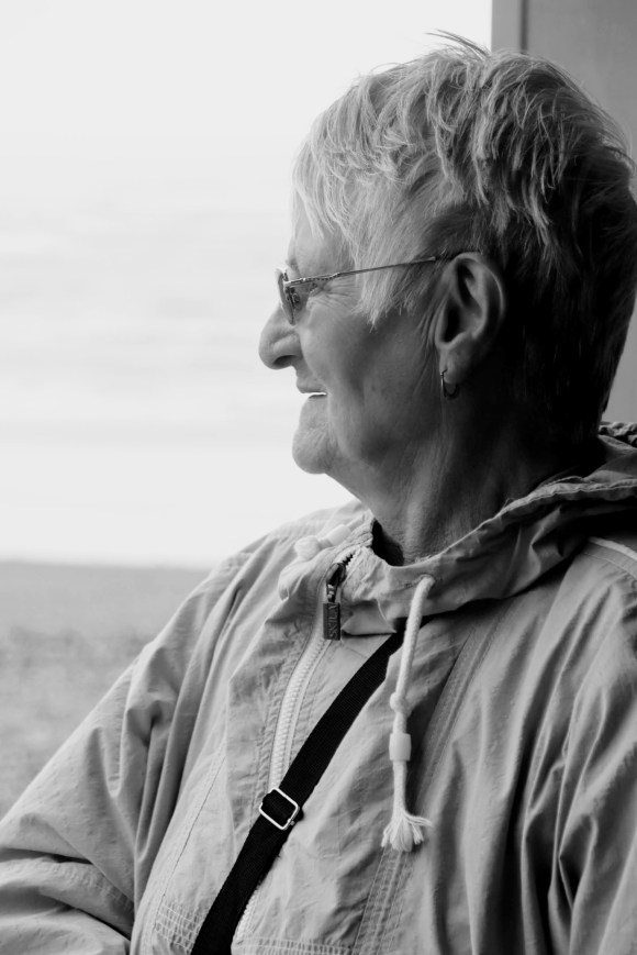 a black and white profile photo of Mary Elizabeth. An elderly lady enjoying the windswept view looking out at eastbourne pier