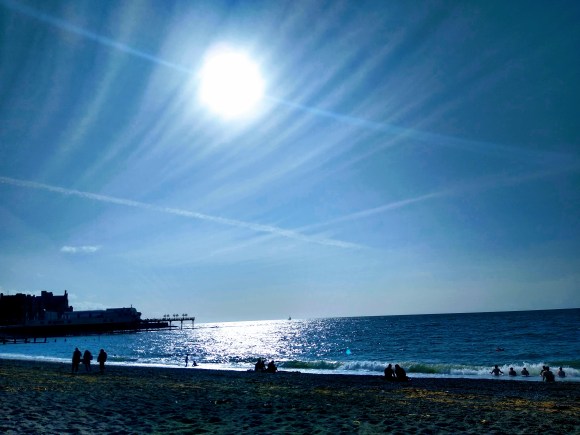 a hazy cloud swept sky overhead Aberystwyth beach with the pier in view