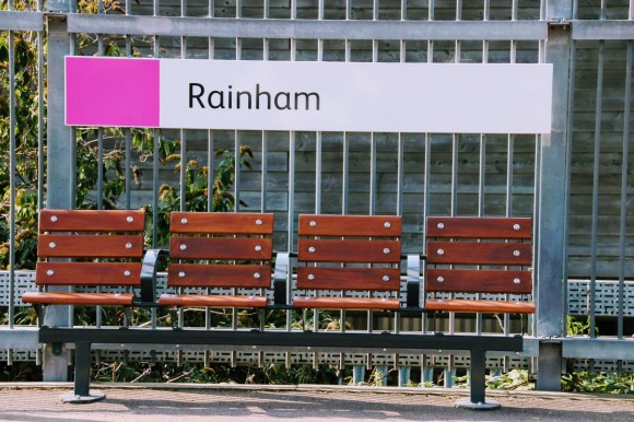 four empty eats on the plrtform under the station sign 'Rainham'