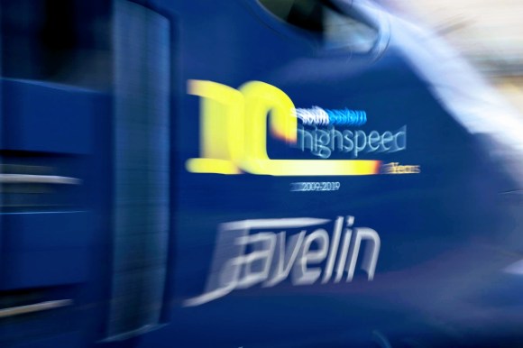 a moving shot of the deep blue engine unit with the following painted on the side: South Eastern 10 High Speed Years 2009-2019 Javelin. The words are stretched created by the panning effect of the shot being taken as the train goes past
