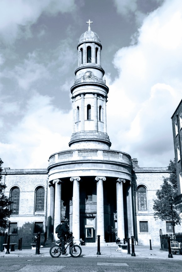 a black and white ground shot looking up at St Mary's Church with its domed top tower prominent against the cloudy blue sky backdrop
