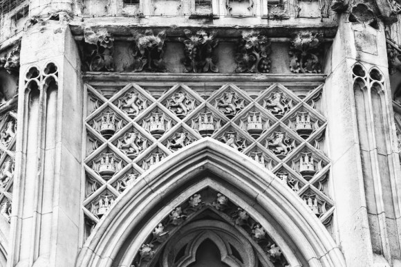 black and white image of a section of the Eleanor Cross outside the station. This section focusses on an array of rampant lions and three turretted castles over an arched window