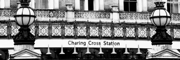 black and white 'letter box' image of the station name viewed through the front railings and flanked by decorative street lights