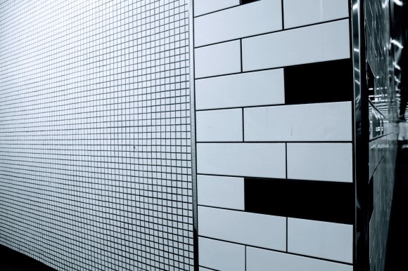 Black & White: a tiled wall of two trypes: small white squares and oblong black and white tiles