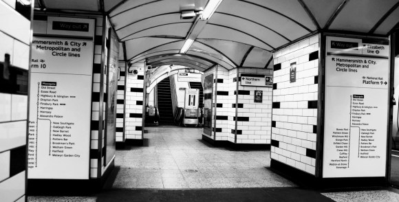 Black & White: a view through the columns leading to escalators from platforms 9 & 10 with column walls covered with destination routes and directional signs