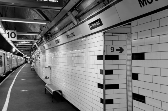 Black & White: long shot down platform 10 with a train waiting to depart and sign through walkway to platform 9 on rhs.