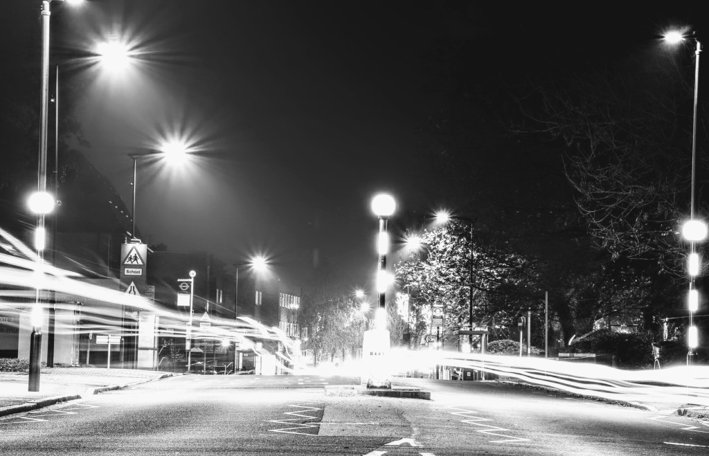 headlight and tail light streaks set against a wintry and slightly foggy night sky