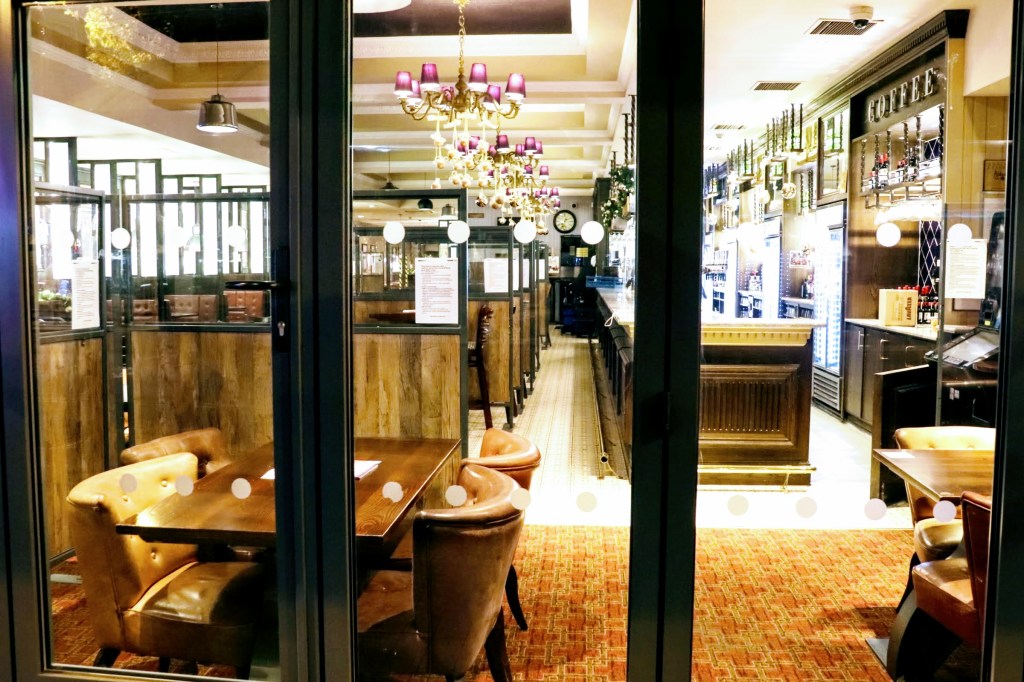 a view through the window looking through an empty bar. all the lights are on