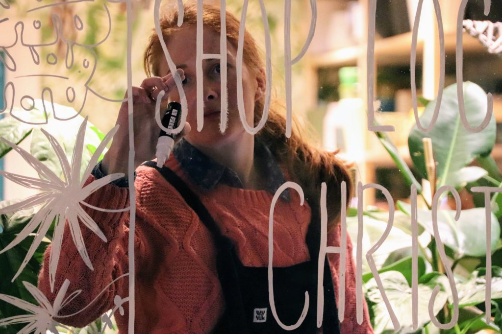 Lydia Packahm inside the shop  painiting the window with decorative leaves