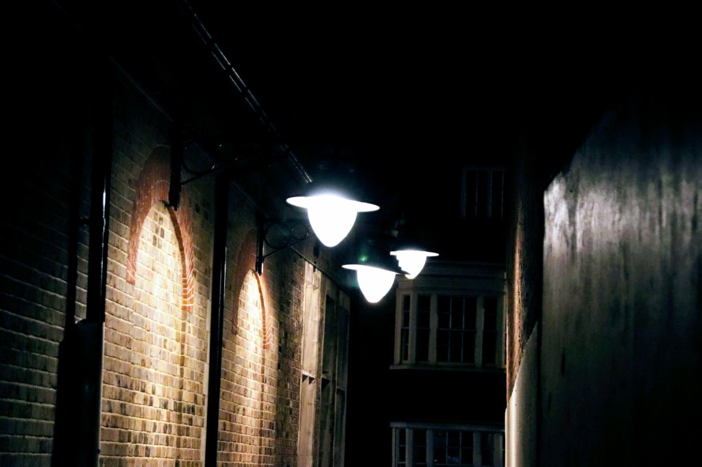 three victorin style street lights shining on a brick wall
